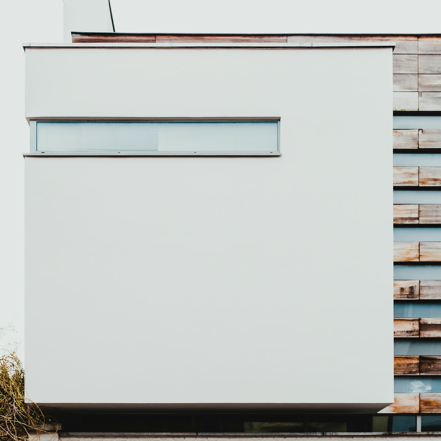 Modernes Gebäude mit weißer Fassade und Holzverkleidung.